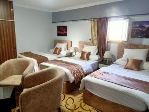 法尤姆فاكانزا شقة فندقية مفروشة- vacanze的酒店客房,设有三张床和椅子