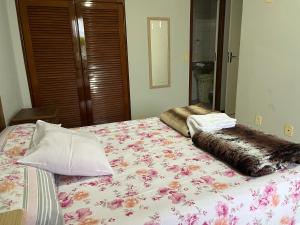 安谢塔Apartamento 3 quartos Beira Mar的一间卧室配有一张带花卉图案的毯子的床
