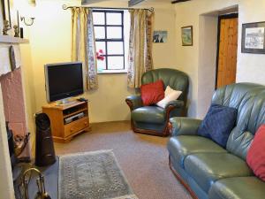 GarrigillHigh Windy Cottage的客厅配有2把皮椅和电视