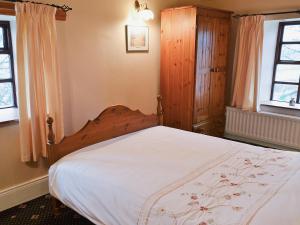 GarrigillHigh Windy Cottage的一间卧室配有一张大床和木制床头板