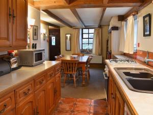 GarrigillHigh Windy Cottage的厨房配有木制橱柜和带微波炉的桌子。