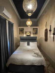 拉巴特Riad AL Bahi的卧室配有一张带吊灯的大型白色床。