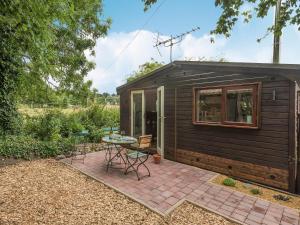Stoke Holy Cross谷仓猫头鹰度假屋的一个小黑棚子,带有庭院和桌子