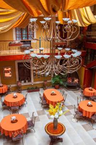 昆卡Hotel Campanario的大型用餐室配有橙色桌子和吊灯。