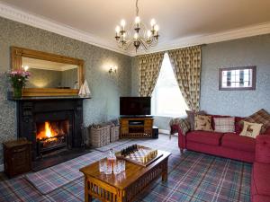 戈尔斯皮Drummuie House的客厅设有壁炉和红色沙发。