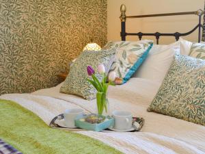 Hollington飞燕草度假屋的床上装有花瓶和两个杯子的托盘