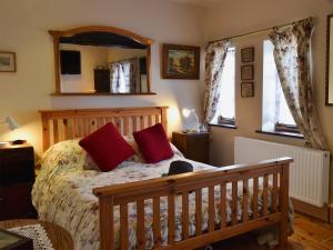 伍尔铁路小屋乡村别墅的一间卧室配有一张带红色枕头和镜子的床