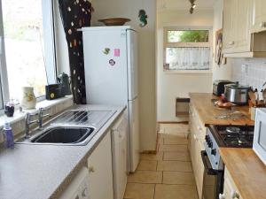 彭赞斯小蓝屋乡村别墅的厨房配有水槽和白色冰箱