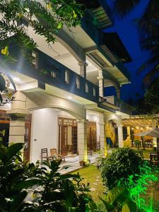 米迪加马东Plantation Surf Inn & Restaurant的一座白色的大建筑,晚上设有庭院