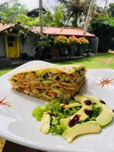 米迪加马东Plantation Surf Inn & Restaurant的三明治和沙拉在白盘上