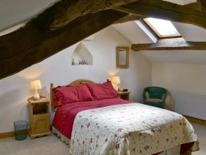 Branthwaite玉米磨坊乡村别墅酒店的一间卧室配有一张带红色床单的床和一扇窗户。