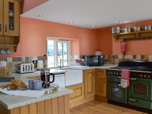 门蒂斯港Graces Cottage的厨房设有橙色墙壁和绿色烤箱