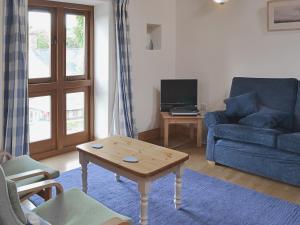 Westbury-sub-MendipThe Threshing Barn的客厅配有蓝色的沙发和茶几