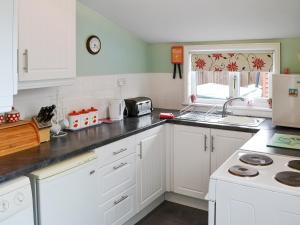 MarthamHalf Moon Cottage的厨房配有白色橱柜和台面