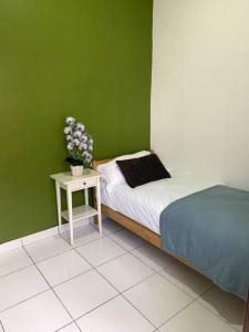 振林山Hud-Hud Homestay 2 Gelang Patah的绿色卧室配有床和鲜花桌