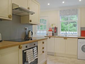 BlairhallFernwoodlea的厨房配有白色橱柜和炉灶烤箱。
