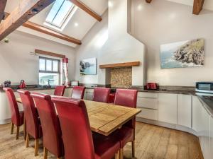 霍利黑德Stack View Cottage的厨房配有木桌和红色椅子