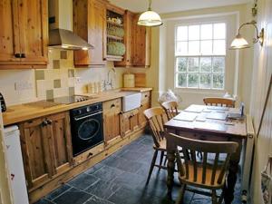 Loders苹果树乡村别墅的厨房配有桌椅和炉灶。