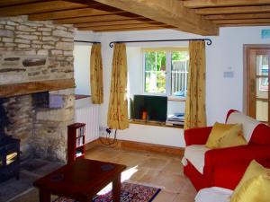 ChedworthIvy Cottage的客厅设有红色的沙发和壁炉