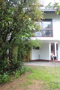 康提Lazy Bear Best Hostel in Kandy的坐在白色房子外椅子上的女人