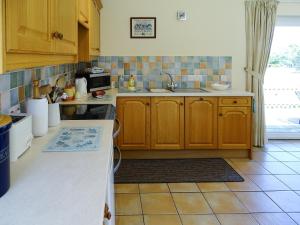 莱斯顿草坪美景度假屋的厨房配有木制橱柜和瓷砖地板。