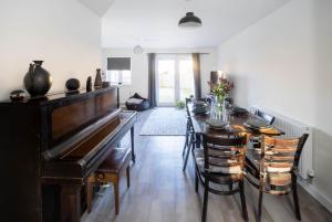 巴恩斯特珀尔Immaculate 3 Bedroom Home Barnstaple Devon的一间带桌子和钢琴的用餐室