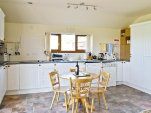 KelsallWeetwood Lodge的厨房配有白色橱柜和桌椅