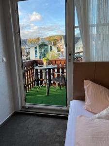 维林根Sevda's Hotel Garni Weinforth的一间卧室设有一扇门,可通往带桌子的阳台