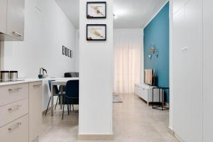 克罗托内Jòia Holiday Home的厨房以及带白色橱柜和蓝色墙壁的用餐室。