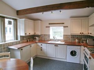 Delph戴尔瑞乡村别墅的厨房配有白色橱柜和水槽