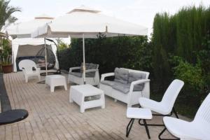 马格达拉Sounds Suite for families的庭院配有白色的椅子和遮阳伞。