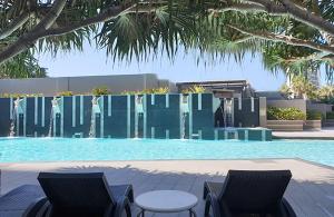 黄金海岸Sealuxe - Central Surfers Paradise - Ocean View Residences的一个带两把椅子的游泳池和一个喷泉