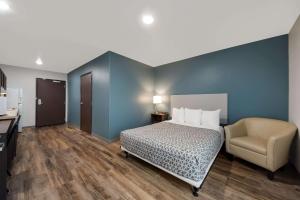 圣安东尼奥WoodSpring Suites San Antonio UTSA - Medical Center的配有一张床和一把椅子的酒店客房