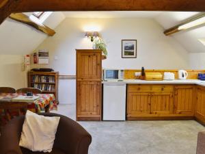 Arthog伊尔汉乡村别墅的厨房配有木制橱柜和白色冰箱。