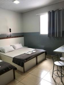 圣保罗Hotel sany - Localizado à 5 minutos do Metrô Paulista的一间卧室配有一张床、一张桌子和一个窗户。