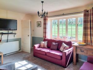 Hovingham豪斯农场乡村别墅的客厅配有紫色沙发和电视