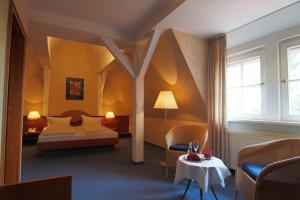 Derenburg德朗堡城堡别墅酒店的一间卧室配有一张床、一把椅子和一张桌子