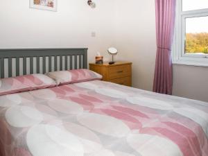 Caeathro依多尔乡村别墅的卧室配有粉色和白色的床,设有窗户