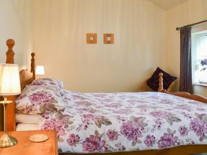 Brynsiencyn玉米阁楼乡村别墅的一间卧室配有一张床和一张带台灯的桌子