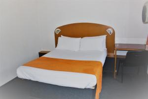 瓦朗斯堡Hôtel Quick Palace Valence Nord的一张带木制床头板的床和一张书桌