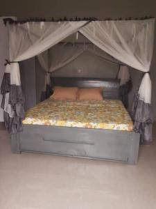 布琼布拉Cheerful 4-bedroom home with parking的一张带两个枕头和天蓬的床