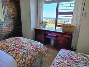 克莱因蒙德La Mer Seafront Selfcatering Accommodation Kleinmond的一间卧室配有一张床、一张书桌和一个窗户。