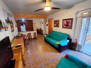 瓜尔达马尔·德尔·塞古拉Apartamento Maite的一间带绿色沙发的客厅和一间厨房