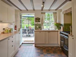 Bellerby樱桃树乡村别墅 的一间厨房,配有白色橱柜,享有庭院的景色
