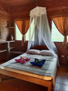 公主港Bambua Nature Cottages的一间卧室配有一张带天蓬的床,并提供毛巾