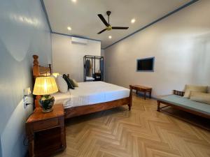 琅勃拉邦Sadakham Hotel的一间卧室配有一张带吊扇和沙发的床。