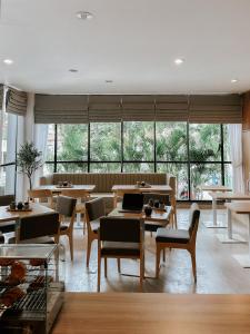 雅加达CASA CALMA HOTEL的餐厅设有桌椅和大窗户。