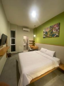 雅加达CASA CALMA HOTEL的卧室配有白色的床和绿色的墙壁