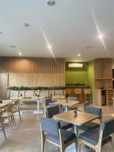雅加达CASA CALMA HOTEL的餐厅设有木桌和椅子,拥有绿色的墙壁