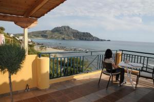 普拉基亚斯塔拉萨之家公寓式酒店的坐在阳台上的桌子旁,欣赏海洋美景的女人